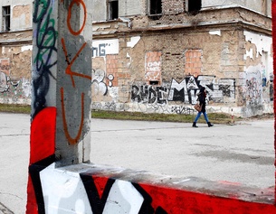 Alltagsaufnahme in Sarajevo, Frau geht an einer Ruine vorbei Graffiti