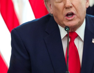 Donald Trumps Oberkörper und Mundpartie, dahinter US-Flagge
