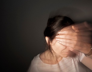 Frau hält sich Stirn