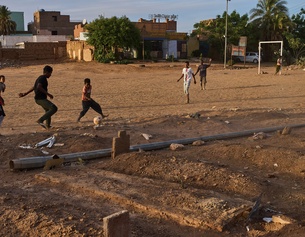 Buben spielen Fußball neben einem provisorischen Friedhof im Sudan
