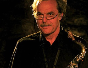APA/KK Porträt von Karlheinz Miklin. Er steht auf der Bühne und hält sein Saxophon.