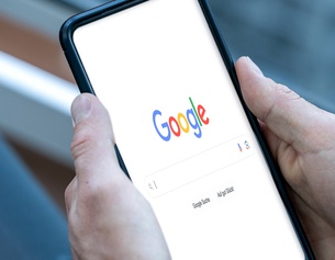 Mann hält Smartphone in Händen - Google Searchbar