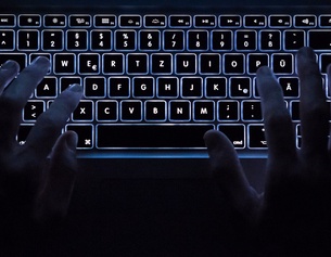 Ein Paar Hände auf einer Computertastatur im Dunkeln