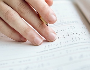 Hand mit Bleistift und Mathematikbuch