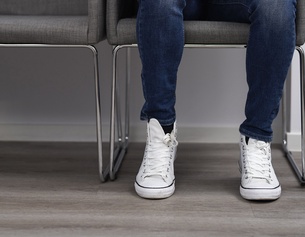 Mann sitzt in einem Wartezimmer, weiße Converse