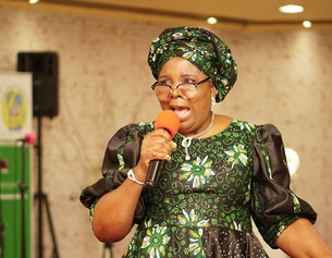 LORD'S PENTECOSTAL EVANGELISTIC MINISTRY Frau in bunter Tracht mit Mikrofon